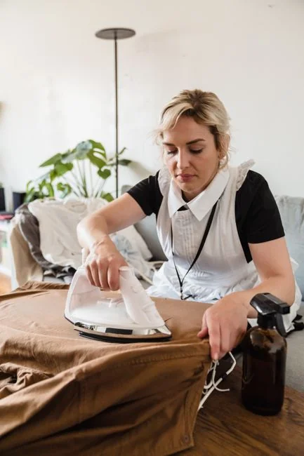 Une femme de chambre range soigneusement des serviettes propres dans une chambre luxueuse.